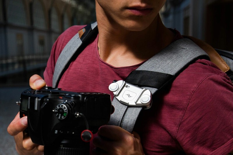 The Peak Design Everyday Backpack being worn by a man removing a camera from the strap mount. 