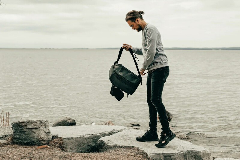 Gomatic McKinnon backpack being held by a man at the beach. 